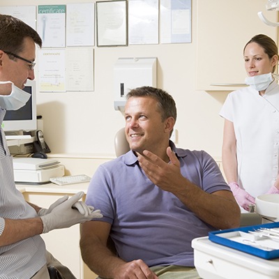 Smiling man in dental chair talking to dentist