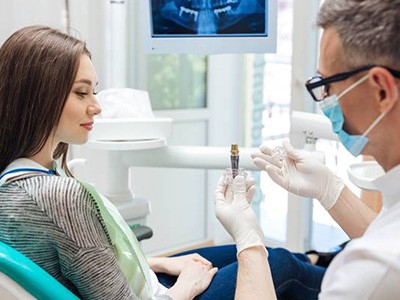 Dentist showing patient dental implant model