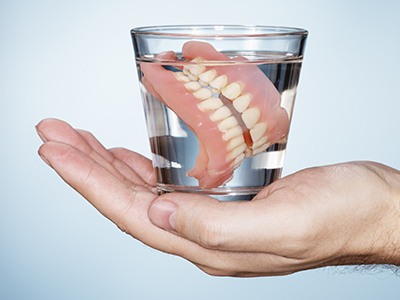 traditional dentures in a glass of water